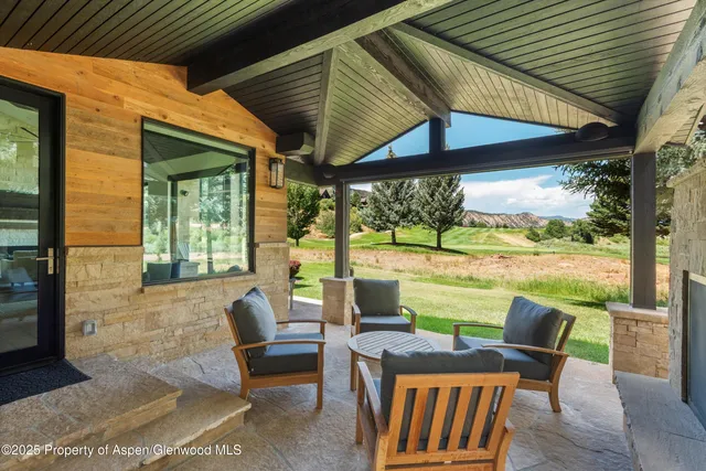 a view of a patio with couches chairs and a floor to ceiling window and a yard