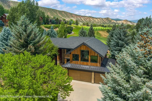 a front view of a house with a garden and trees