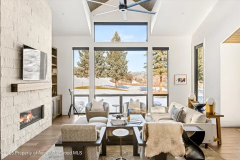 a living room with fireplace furniture and a large window