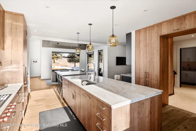 a large kitchen with kitchen island a stove a sink a refrigerator and a wooden floor