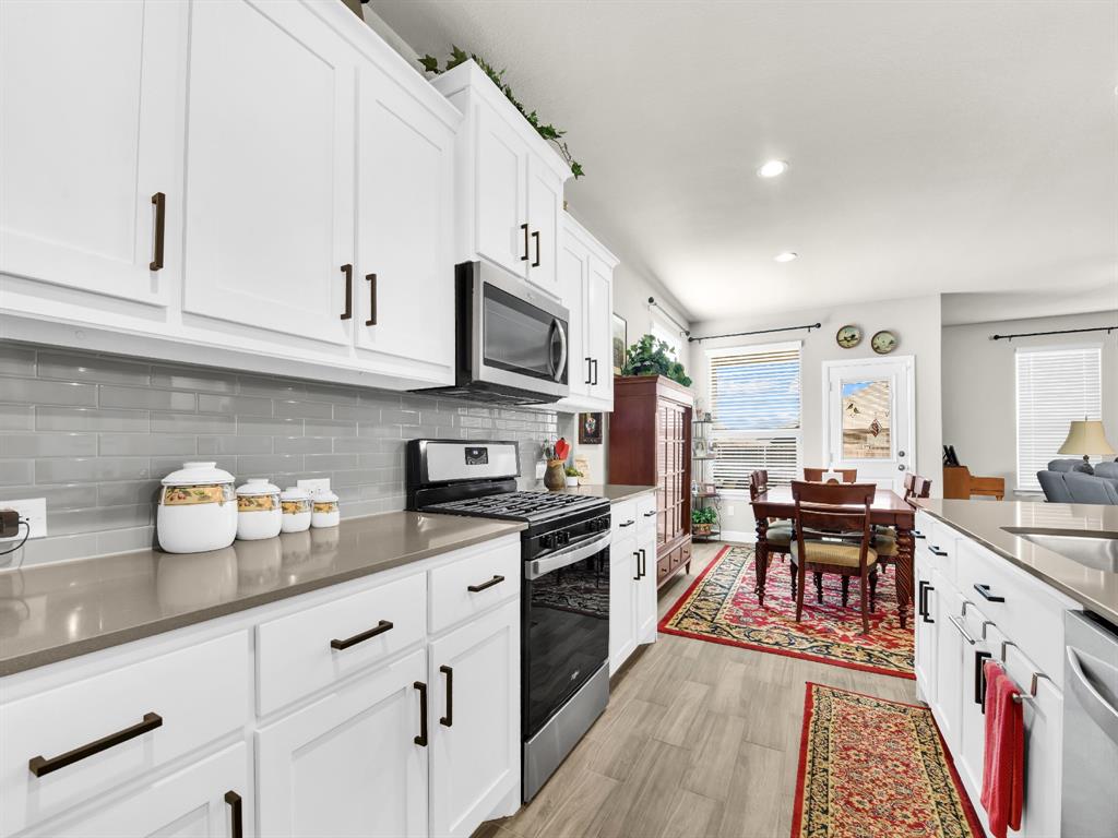 2364 Waggoner Rnch Drive Weatherford, TX 76087 - Photo 11 of 30 a kitchen with stainless steel appliances granite countertop a stove top oven a sink dishwasher and white cabinets with wooden floor