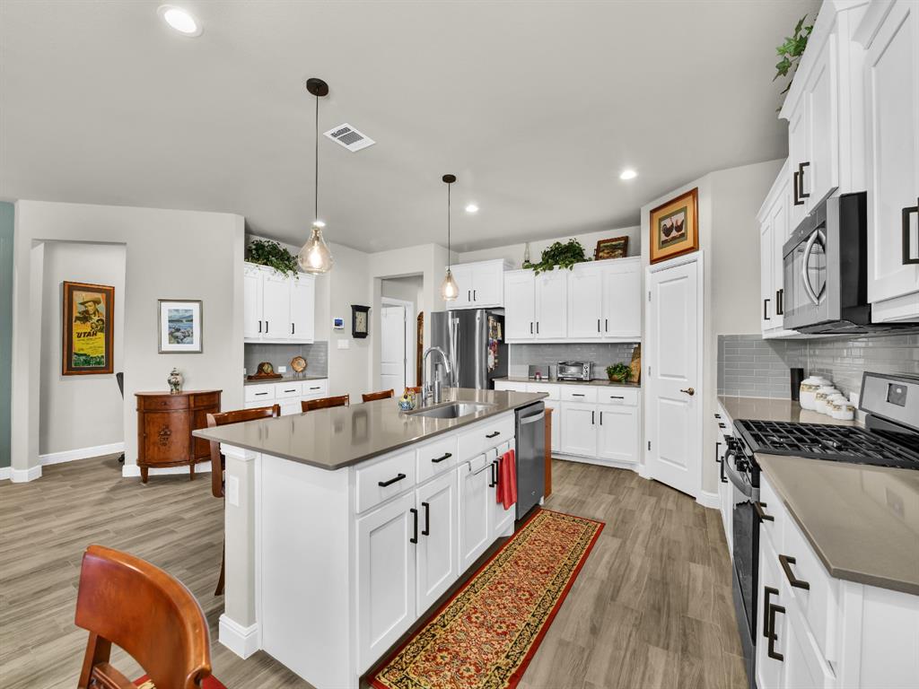 2364 Waggoner Rnch Drive Weatherford, TX 76087 - Photo 12 of 30 a large kitchen with stainless steel appliances granite countertop a stove oven a refrigerator a sink dishwasher and white cabinets with wooden floor