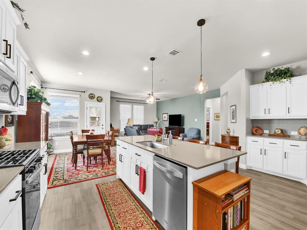2364 Waggoner Rnch Drive Weatherford, TX 76087 - Photo 13 of 30 a large kitchen with kitchen island a stove a sink a dining table and chairs with wooden floor