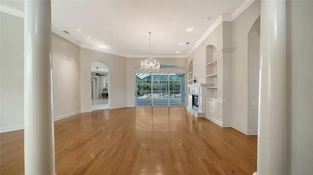 a view of an empty room with wooden floor fireplace and a window