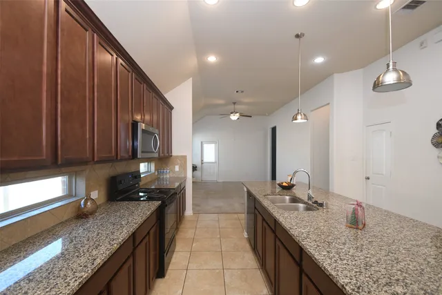 a large kitchen with granite countertop a sink and cabinets