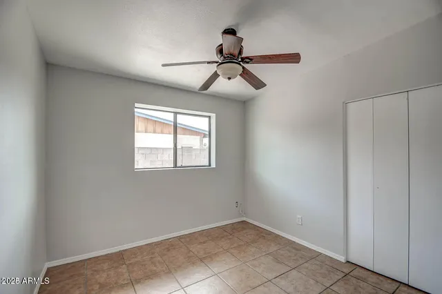 an empty room with a ceiling fan and carpet