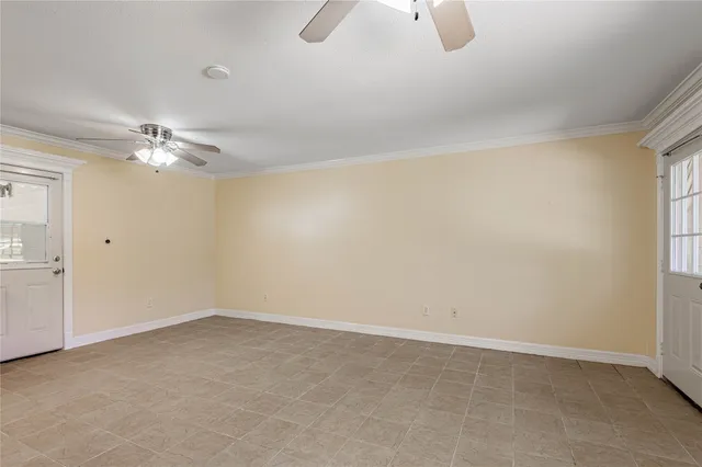 an empty room with chandelier fan and windows