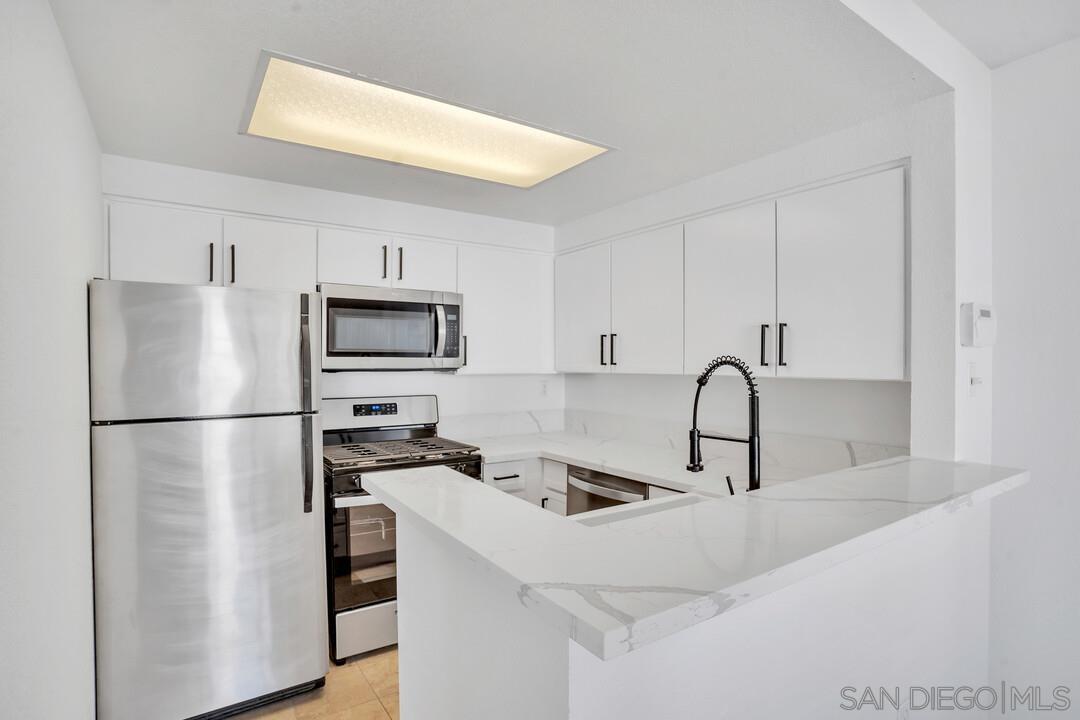 a kitchen with stainless steel appliances a refrigerator sink and white cabinets