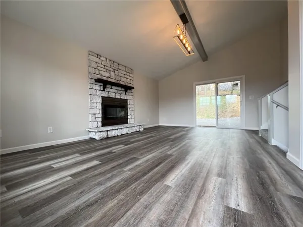 a view of an empty room with wooden floor fireplace and a window