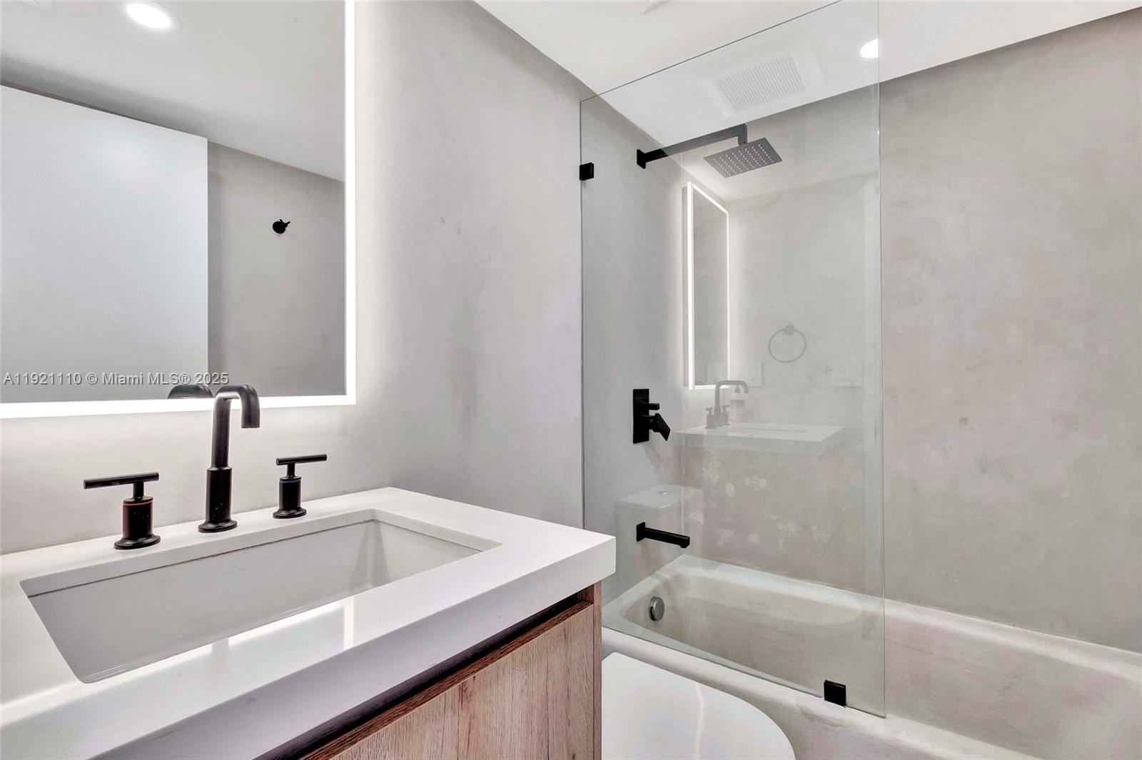 1627 Brickell Avenue, Unit 1202 Miami, FL 33129 - Photo 22 of 30 a bathroom with a tub sink and mirror