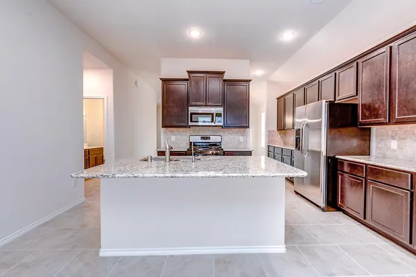 a large kitchen with stainless steel appliances granite countertop a sink a stove and a refrigerator