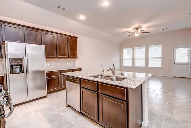 a kitchen with kitchen island granite countertop a sink stove and refrigerator