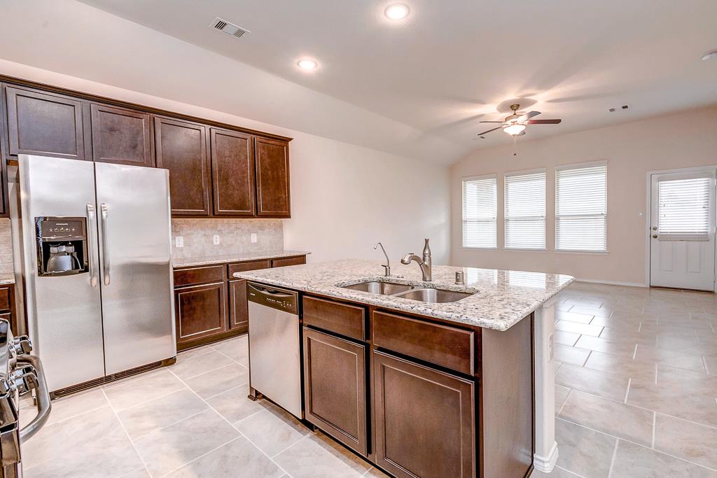 24314 North Newcastle Bay Trail Spring, TX 77389 - Photo 16 of 32 a kitchen with kitchen island granite countertop a sink stove and refrigerator