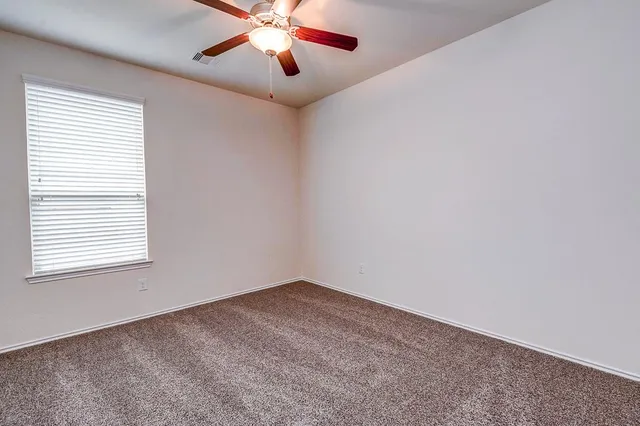 an empty room with a window and a fan