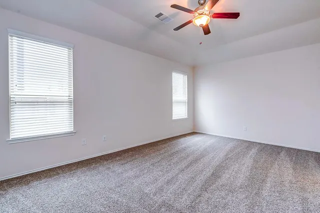 a view of an empty room with window and a chandelier fan