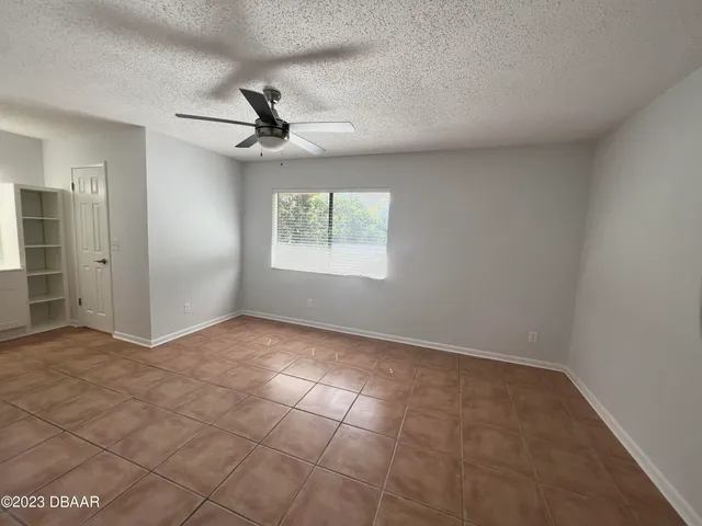 an empty room with windows and fan