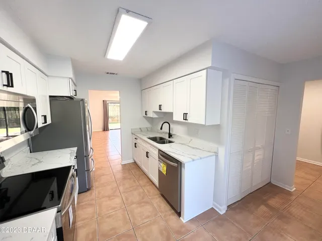 a large kitchen with stainless steel appliances granite countertop a stove a sink and a refrigerator