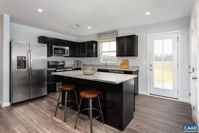 a kitchen with stainless steel appliances granite countertop a sink a stove a microwave a refrigerator and island