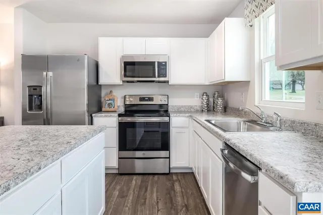 a kitchen with granite countertop a sink stove and microwave