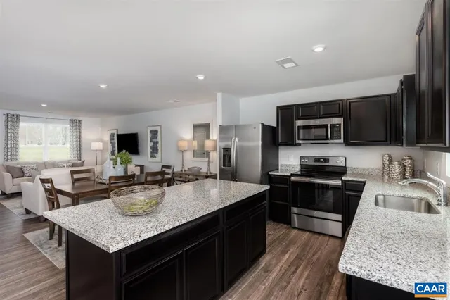 a kitchen with kitchen island granite countertop stainless steel appliances stove microwave refrigerator and sink