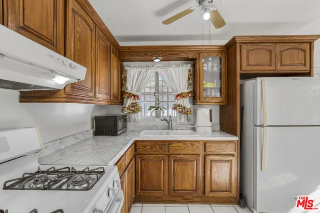 a kitchen with kitchen island a stove a refrigerator and a sink with wooden floor