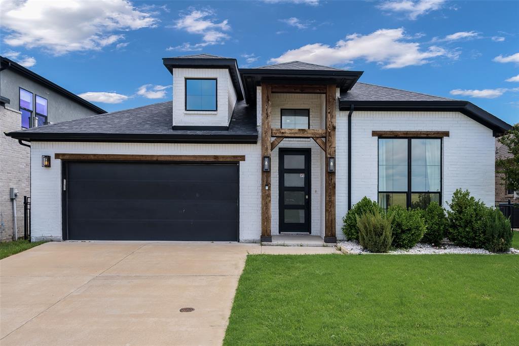 View of front facade featuring brick siding, concrete driveway, a front lawn, a garage, and a shingled roof