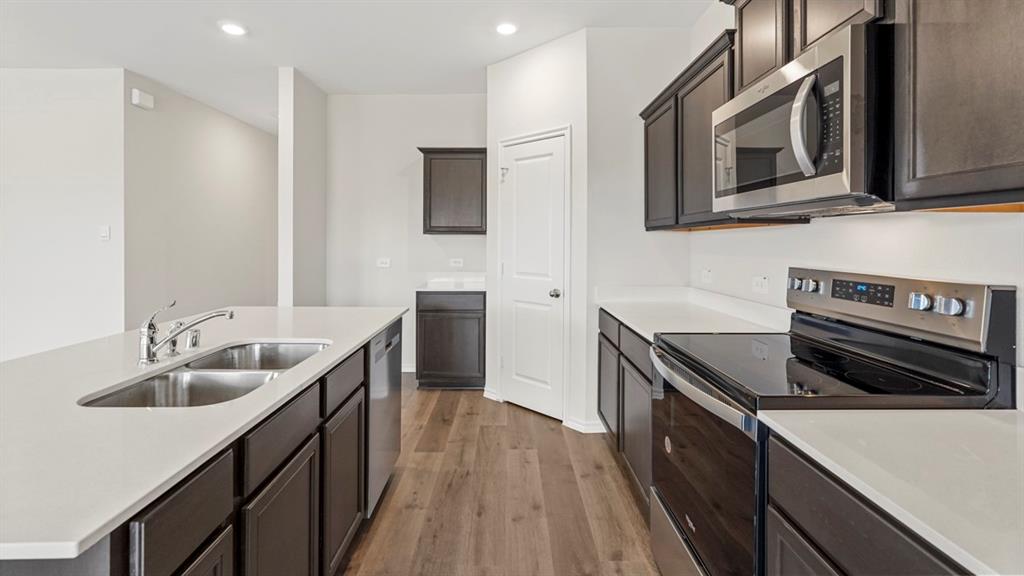 1969 Freeman Street Tyler, TX 75704 - Photo 5 of 30 Modern kitchen featuring dark wood-finish cabinetry, light countertops, a stainless steel double basin sink, and wood-finish flooring