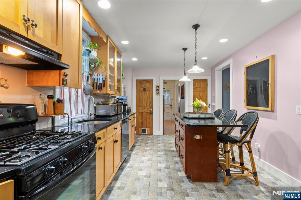 370 Undercliff Avenue Edgewater, NJ 07020 - Photo 14 of 35 a kitchen with stainless steel appliances granite countertop a stove top oven a dining table and chairs with wooden floor