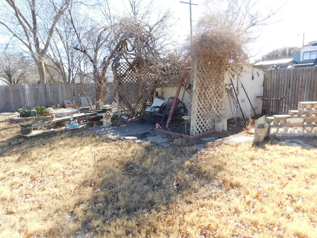 a view of backyard with wooden fence and a large tree
