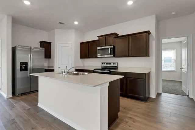 a view of kitchen with microwave stove refrigerator and cabinets