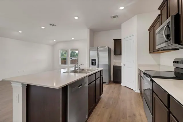 a kitchen with stainless steel appliances a stove microwave and sink
