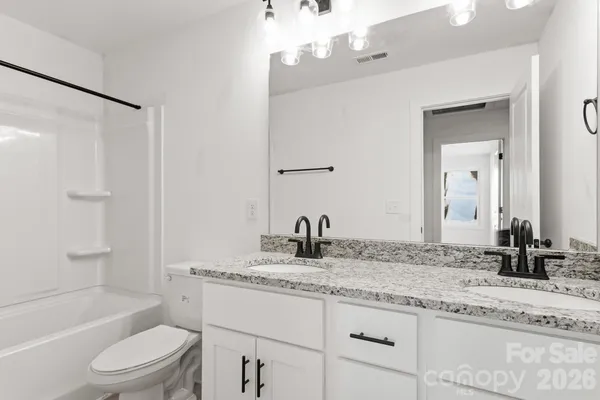 a bathroom with a granite countertop sink a toilet and shower