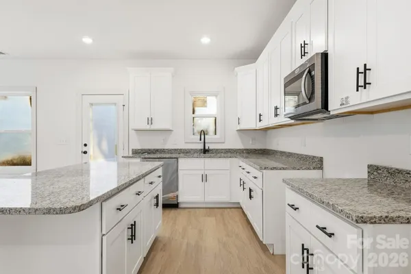 a kitchen with granite countertop white cabinets and stainless steel appliances