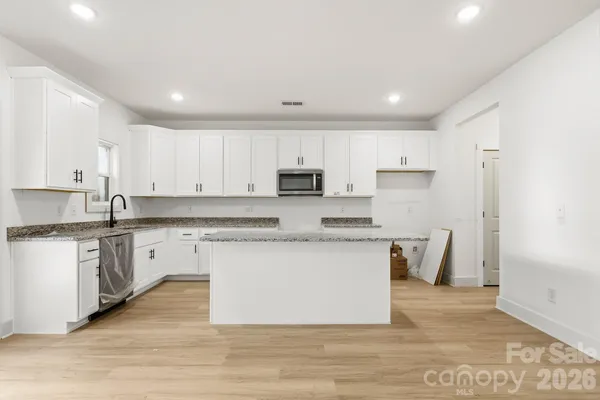 a kitchen with stainless steel appliances granite countertop a white stove top oven a refrigerator and white cabinets