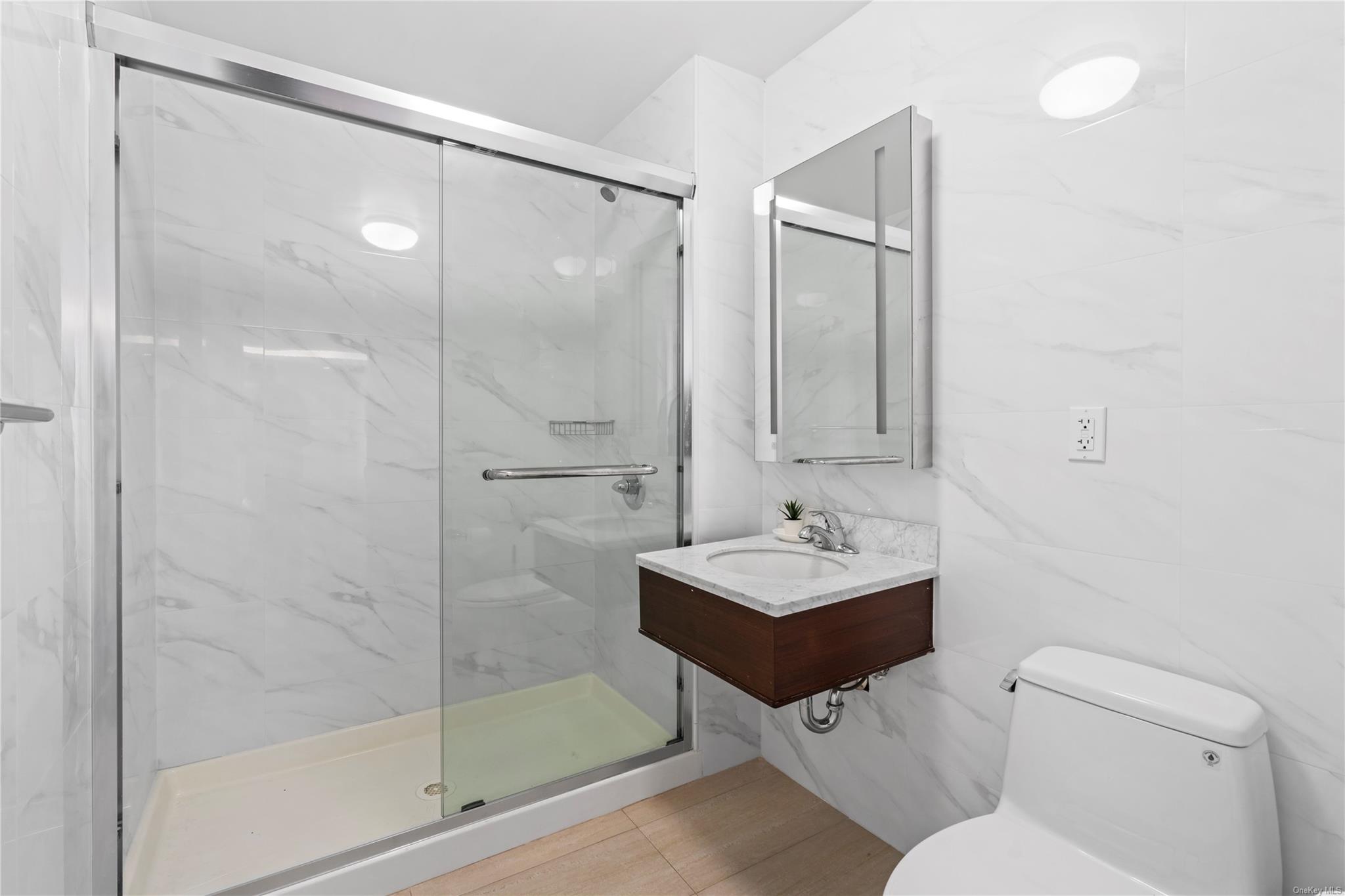 136-46 41st Avenue, Unit 6A Queens, NY 11355 - Photo 26 of 34 Bathroom featuring tile walls, toilet, walk in shower, and sink