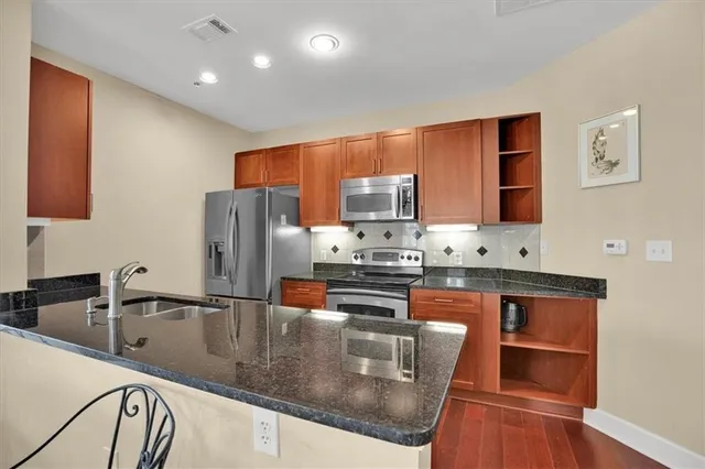 a kitchen with stainless steel appliances granite countertop a stove a sink and a refrigerator