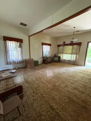 a view of an empty room and a kitchen