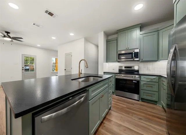 a kitchen with stainless steel appliances granite countertop a sink a stove and a refrigerator