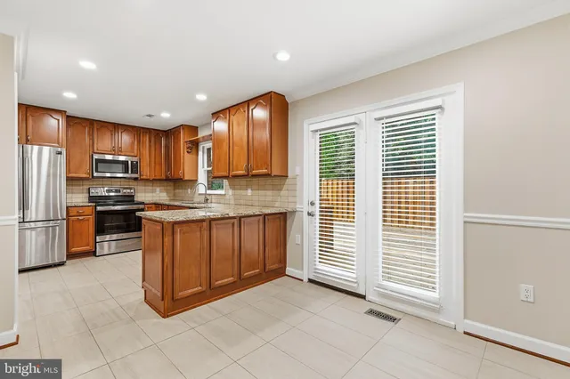 a kitchen with stainless steel appliances granite countertop a refrigerator and a stove top oven