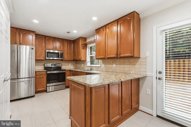 a kitchen with granite countertop a refrigerator and a stove top oven