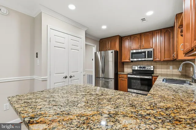 a kitchen with stainless steel appliances granite countertop a refrigerator stove microwave and sink
