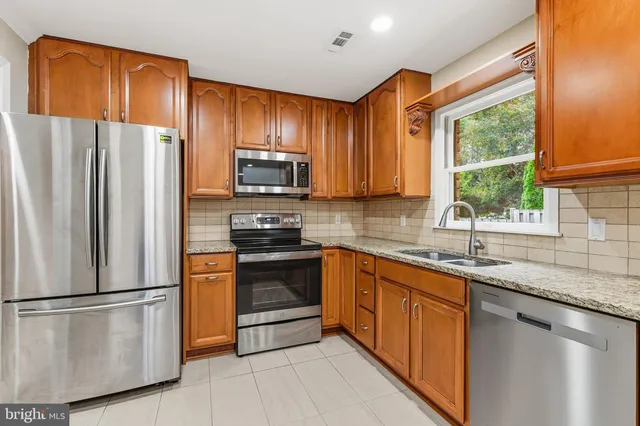 a kitchen with granite countertop wooden cabinets stainless steel appliances and a refrigerator