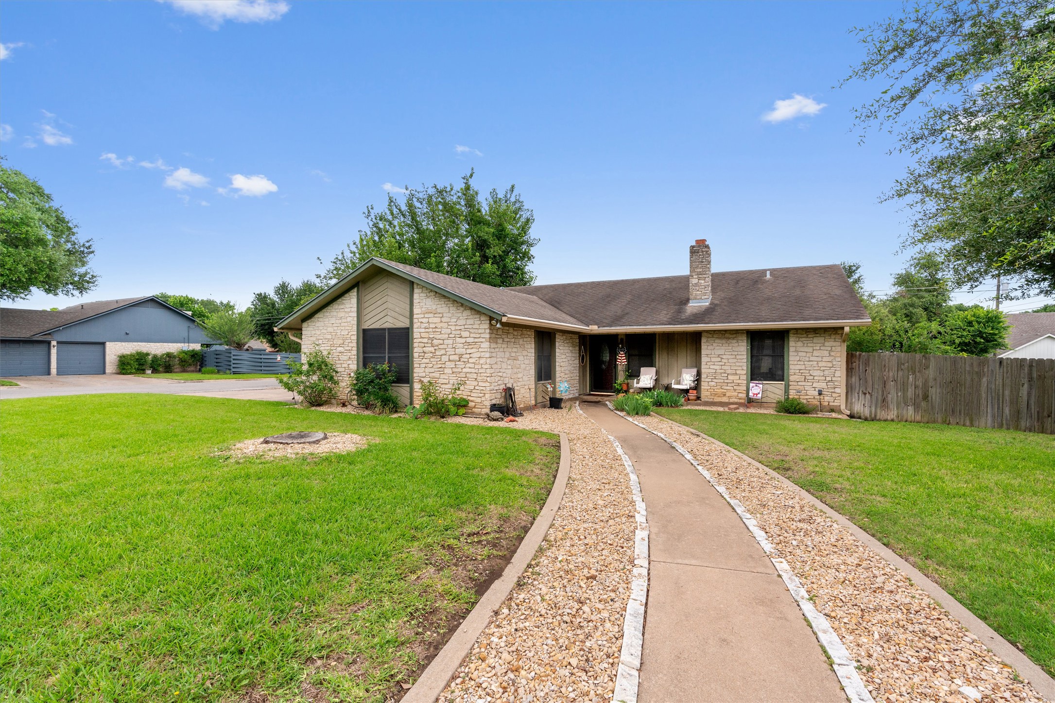 Stone veneer exterior featuring a prominent chimney and a front porch