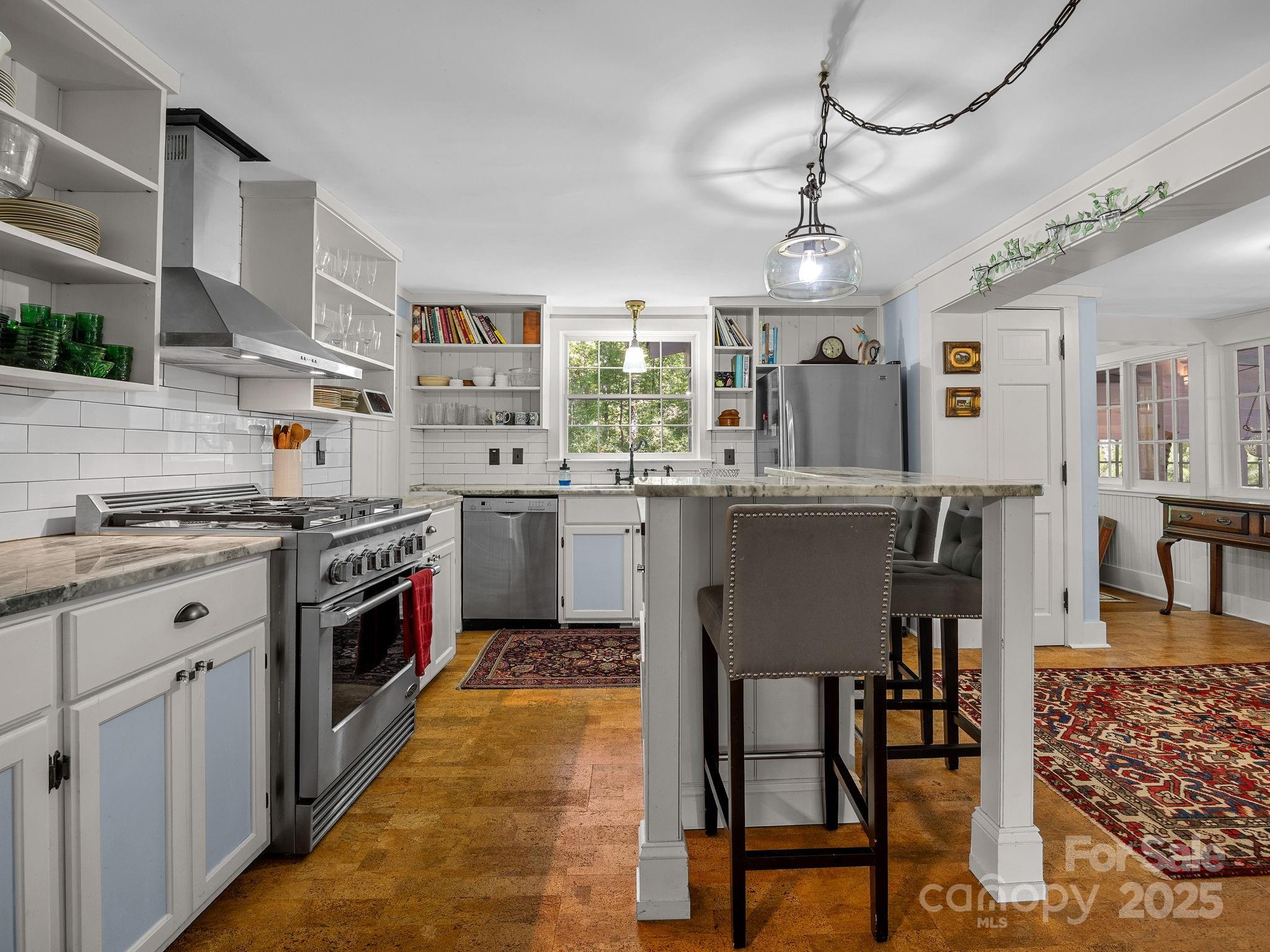 144 Miller Drive Tryon, NC 28782 - Photo 12 of 45 a kitchen with stainless steel appliances granite countertop a stove a sink dishwasher a dining table and chairs with wooden floor