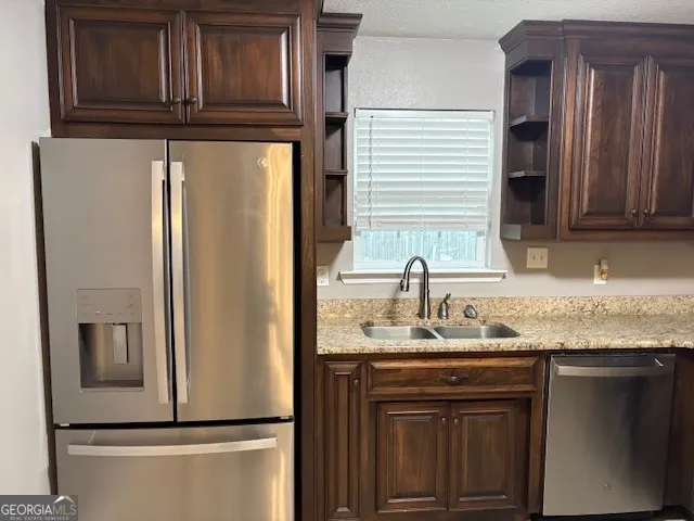 a kitchen with stainless steel appliances granite countertop a refrigerator and a sink