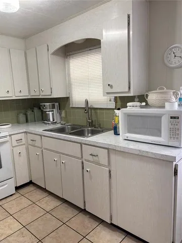 a kitchen with white cabinets and sink