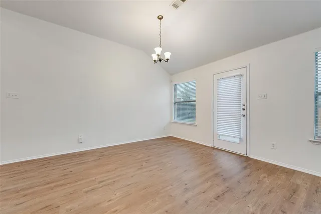 an empty room with wooden floor ceiling fan and window