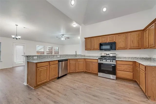 a large kitchen with granite countertop a stove top oven a sink a counter space and cabinets