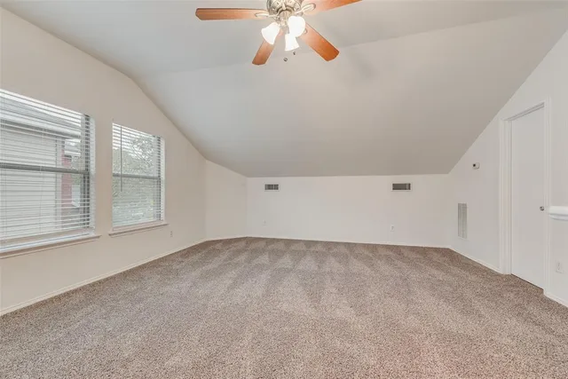 a view of an empty room with chandelier fan and fire place