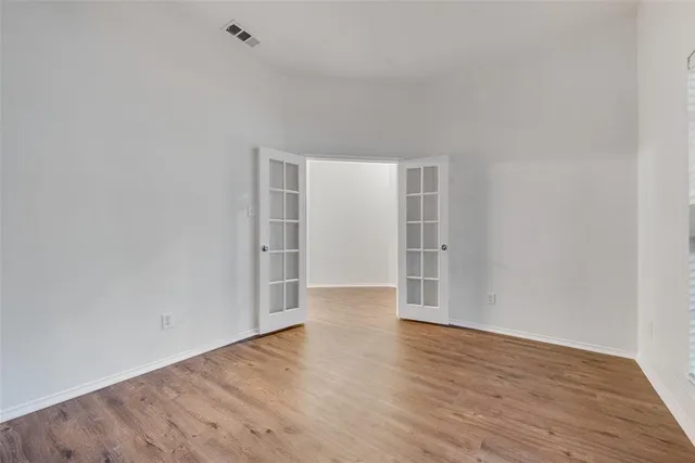 a view of an empty room with wooden floor and closet